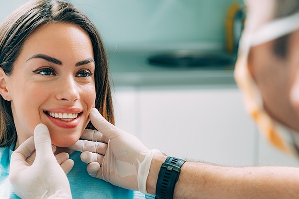 Dentist examining patient's teeth and gums in clinical dental office setting.