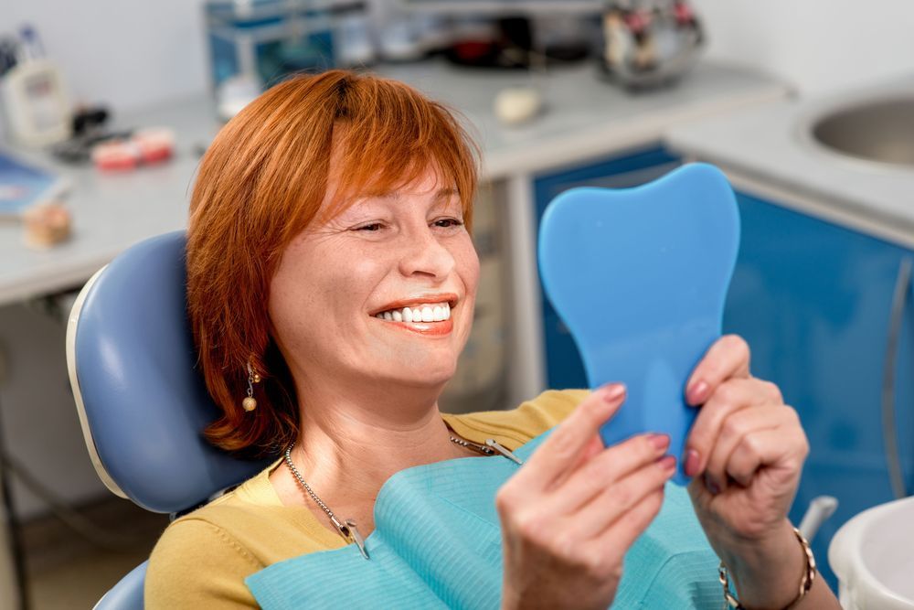 Woman dentist examining blue tooth model in dental office treatment room.