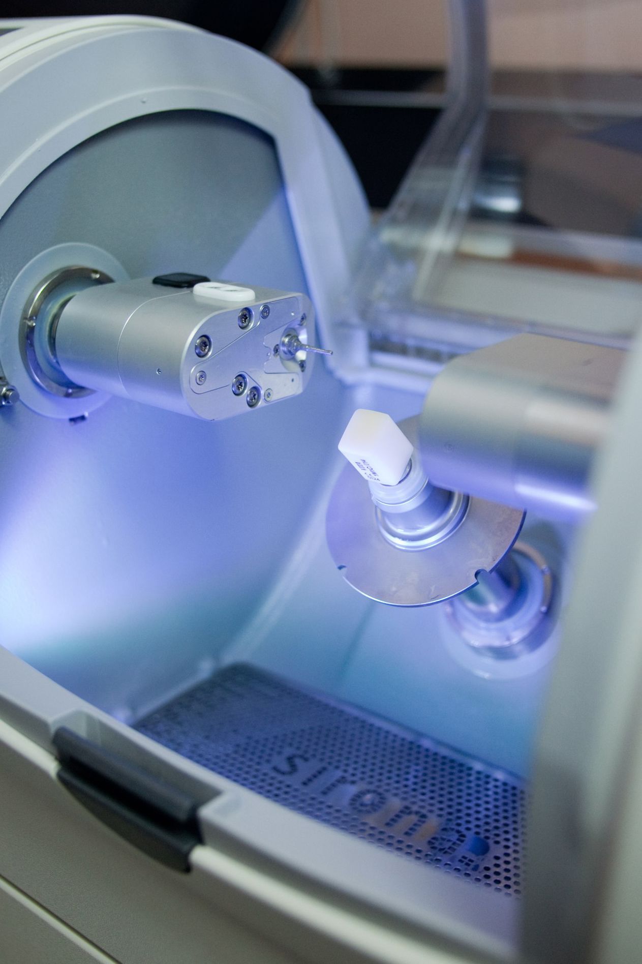 Dental sterilization equipment with blue UV light illuminating instruments inside chamber.