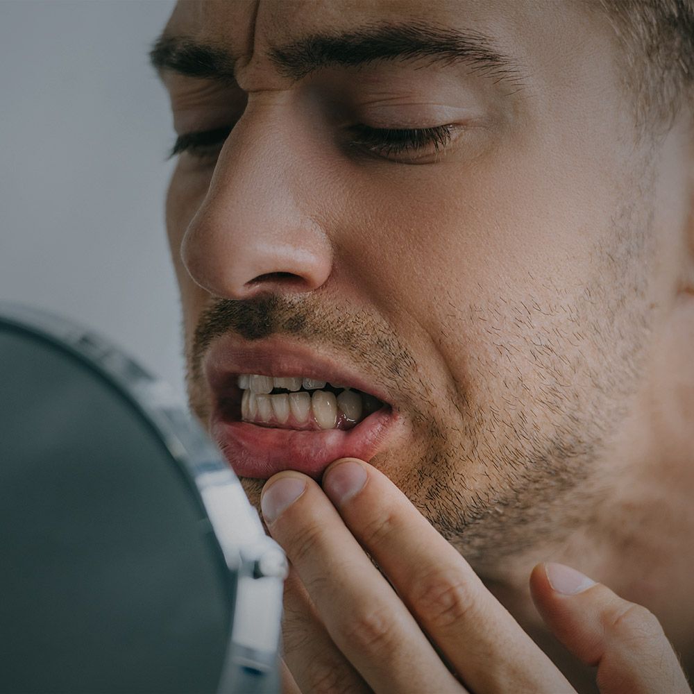 Man touching jaw in pain, eyes closed, expressing dental discomfort or toothache.