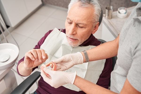 Senior man receiving dental care instruction on proper hand hygiene in modern dental office.