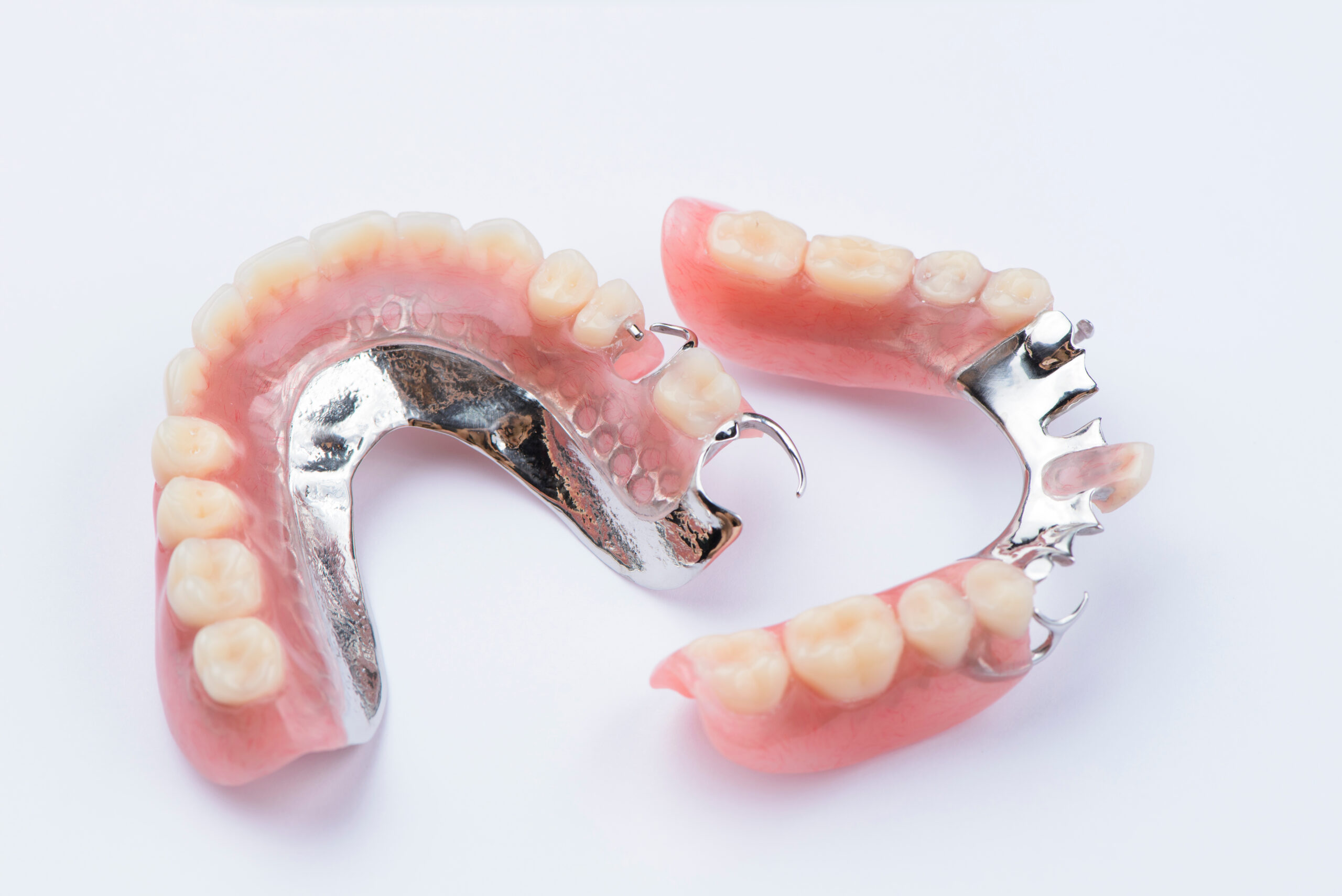 Dental prosthetics and implants displayed on white background showing partial dentures and fixtures.
